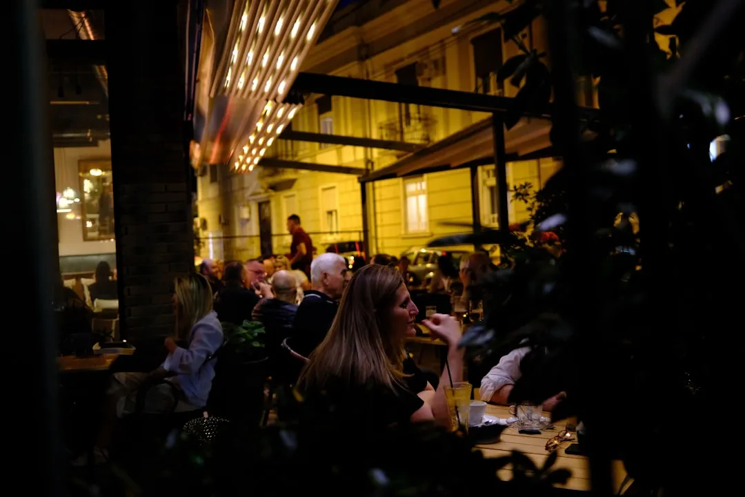 People enjoying an evening meal at a lively outdoor restaurant.
