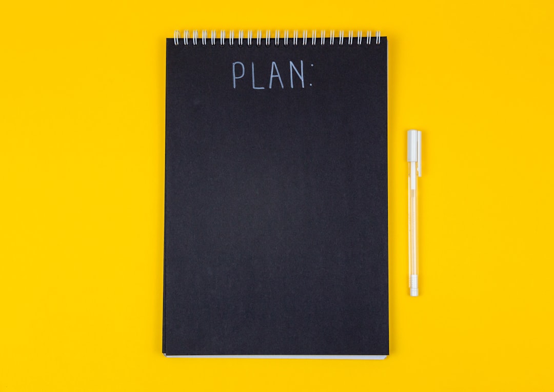 A black spiral notebook with the word PLAN written on a yellow background