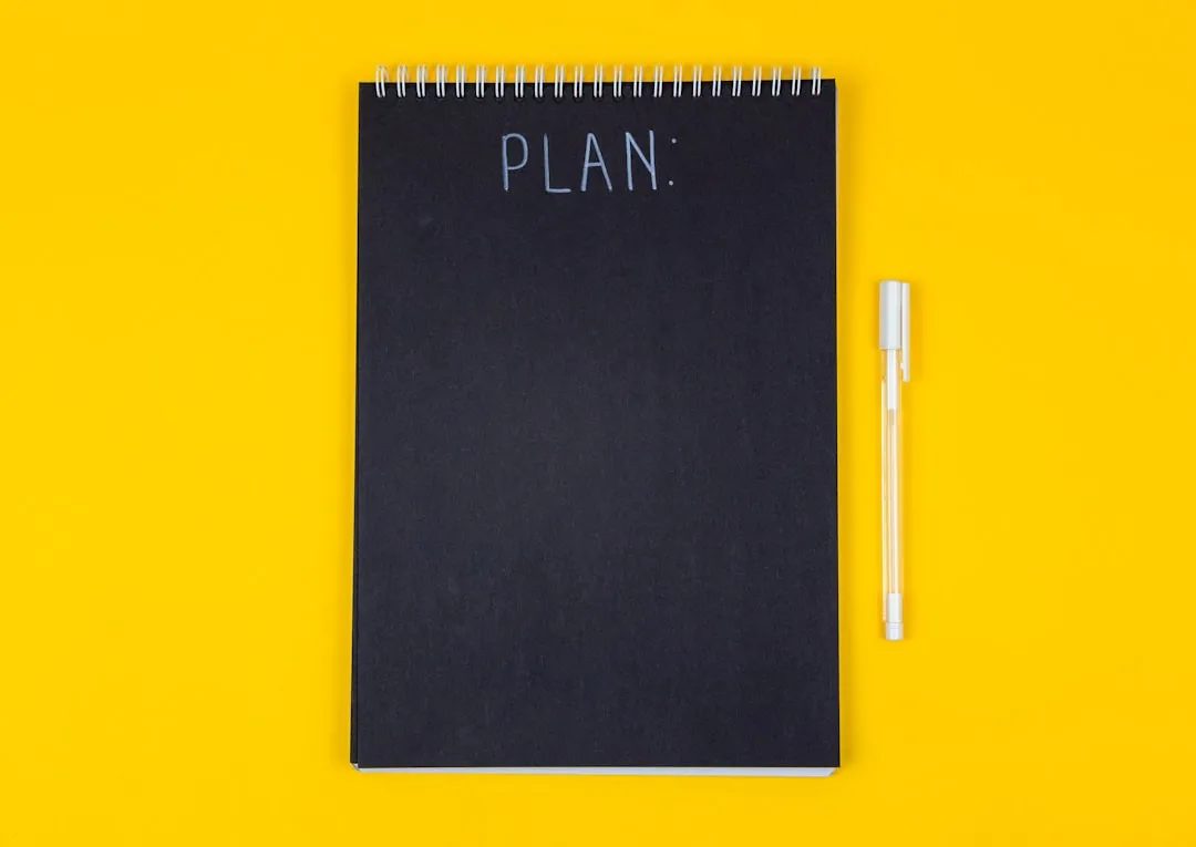 A black spiral notebook with the word PLAN written on a yellow background