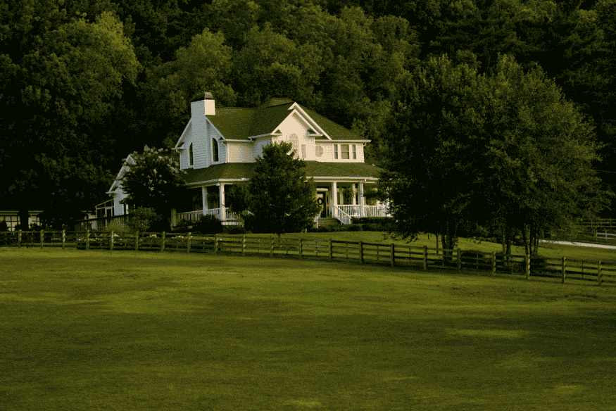 Casa de campo moderna com telhado inclinado cercada por vegetação e gramado.