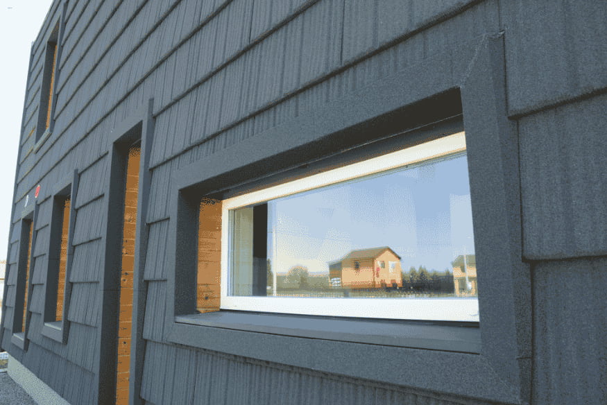 Fachada de casa com revestimento sustentável e janelas eficientes em energia.