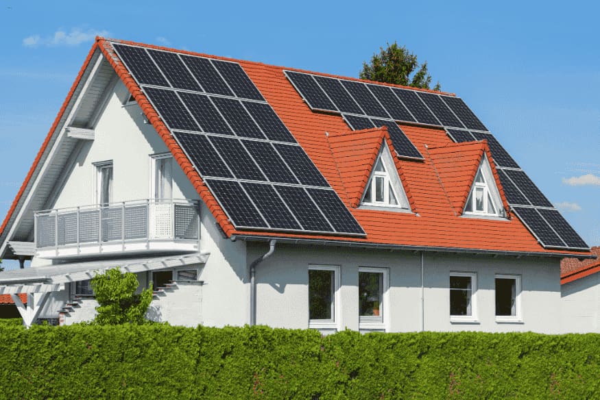 Casa branca com telhado vermelho equipada com painéis solares.