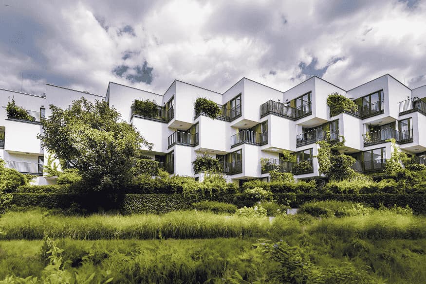 Conjunto residencial moderno com design sustentável e fachadas cobertas por vegetação.