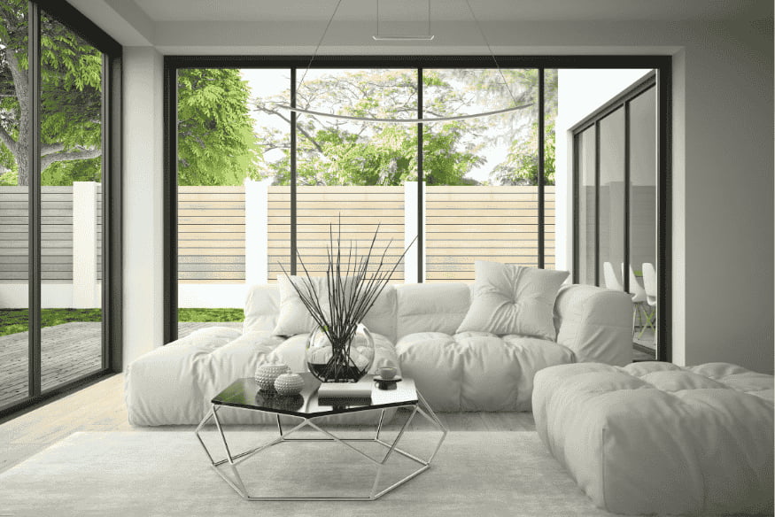Sala ampla com sofá branco modular e tapete claro delimitando a área de convivência.