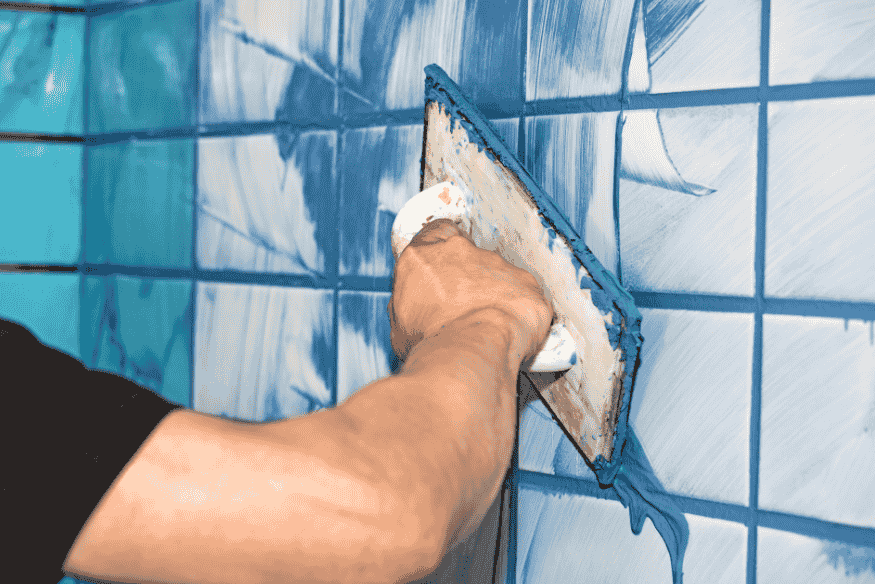 Aplicação de rejunte azul em azulejos de banheiro.