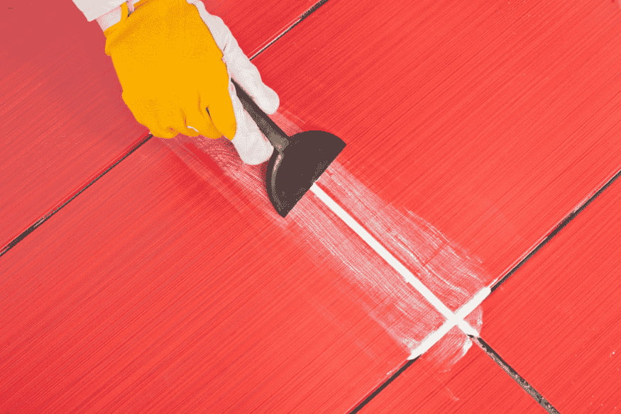 Aplicação de rejunte branco em piso cerâmico vermelho.