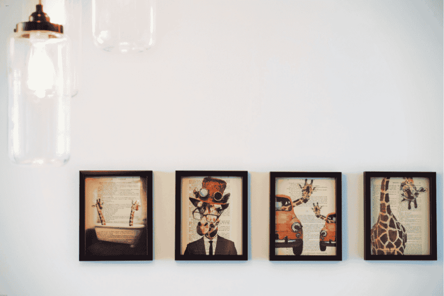 Quadros decorativos com ilustrações de girafas e carros vintage em molduras pretas para parede branca
