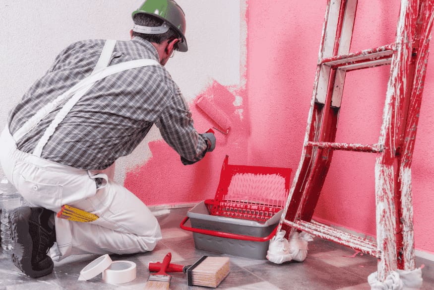 Homem pintando parede interna de rosa com rolo de pintura.