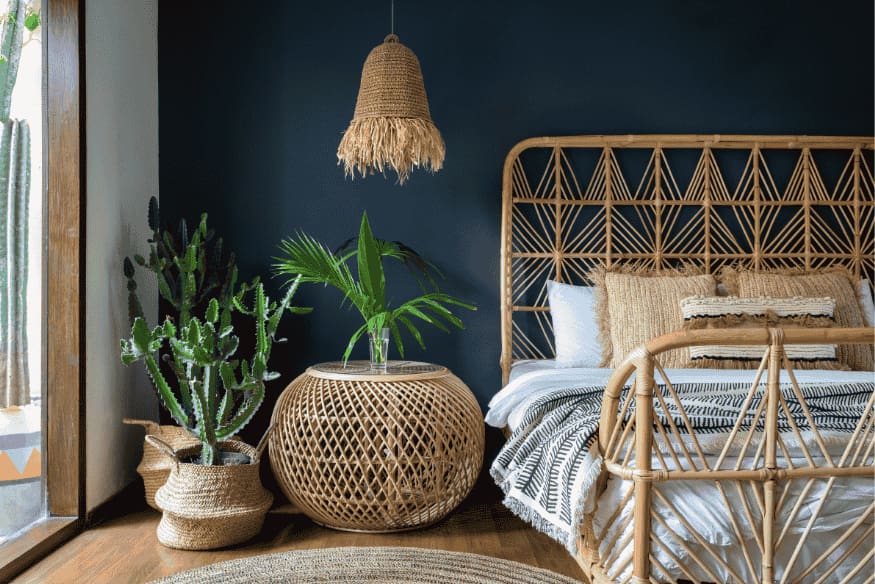 Quarto boho com cabeceira de vime, luminária de fibras naturais e plantas em vasos decorativos.