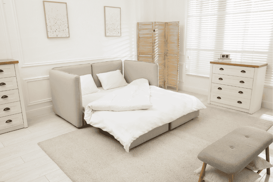 Quarto minimalista em imóvel alugado com sofá-cama, móveis claros e divisória de madeira.