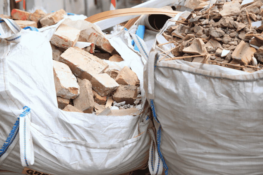 Sacos big bags cheios de restos de concreto, tijolos e pedras de obra.