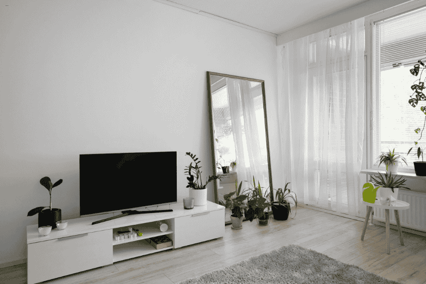 Sala minimalista com espelho apoiado no chão, trazendo sensação de amplitude.