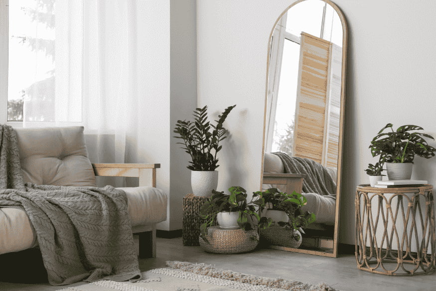 Sala aconchegante com espelho de corpo inteiro e plantas, ampliando o ambiente.