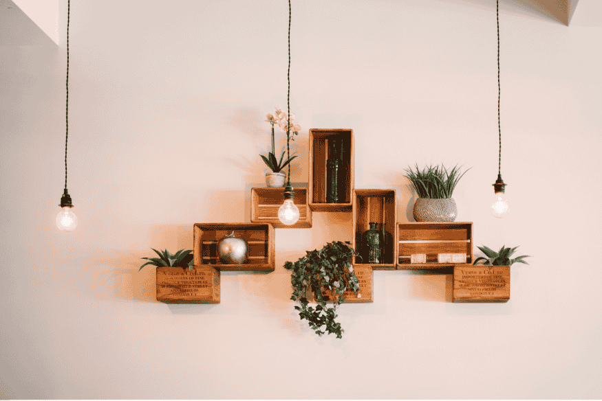 Estante de parede feita com caixotes de feira decorada com plantas e objetos.