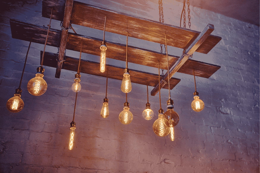 Lustre industrial com lâmpadas de filamento Edison penduradas em estrutura de madeira.