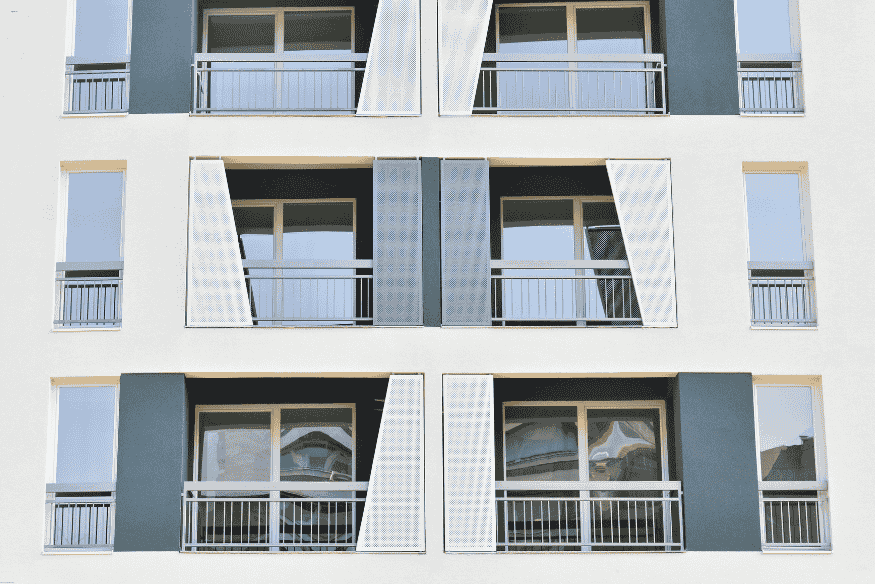 Fachada contemporânea de edifício com painéis metálicos móveis e esquadrias de vidro.