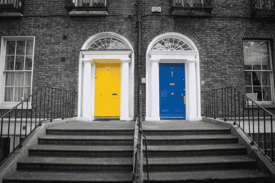 Portas de entrada modernas em cores contrastantes, amarela e azul, em fachada de tijolos.
