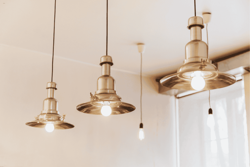 Luminárias pendentes metálicas com lâmpadas de luz quente em ambiente interno minimalista.