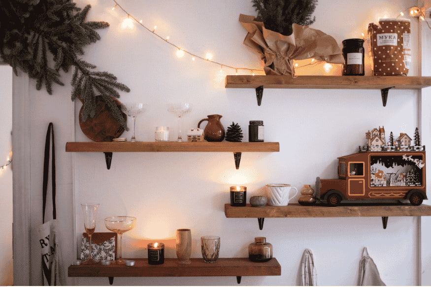 Prateleiras de madeira decoradas com velas, plantas e objetos iluminadas por luzes.