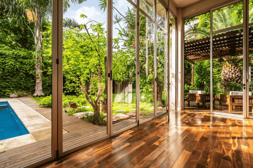 Portas de vidro panorâmicas com vista para jardim e piscina em residência moderna.