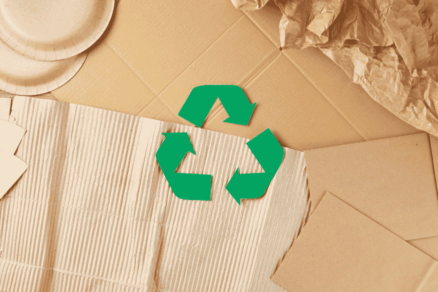 Símbolo de reciclagem sobre papelão e papel reciclável.