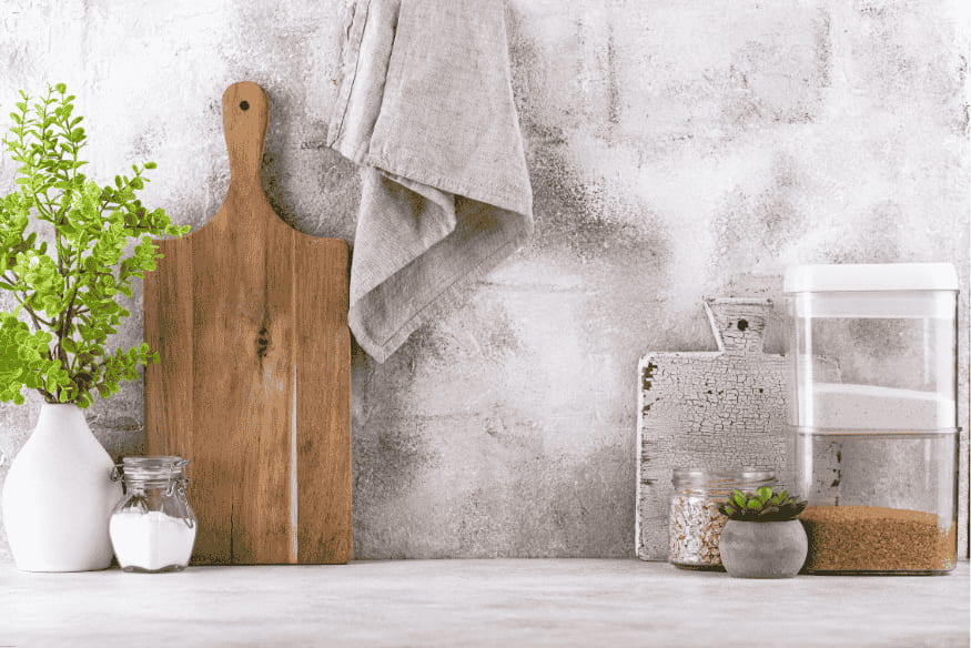 Bancada de cozinha compacta com tábuas de corte, potes e plantas decorativas.