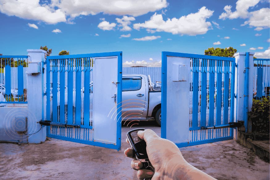 Portão automático de metal azul sendo aberto por controle remoto.
