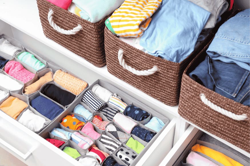 Gavetas organizadas com divisórias e cestos para roupas e acessórios.