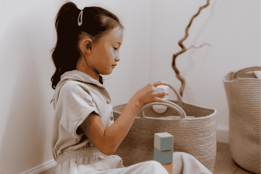 Menina brincando com blocos de montar ao lado de cestos organizadores de tecido.