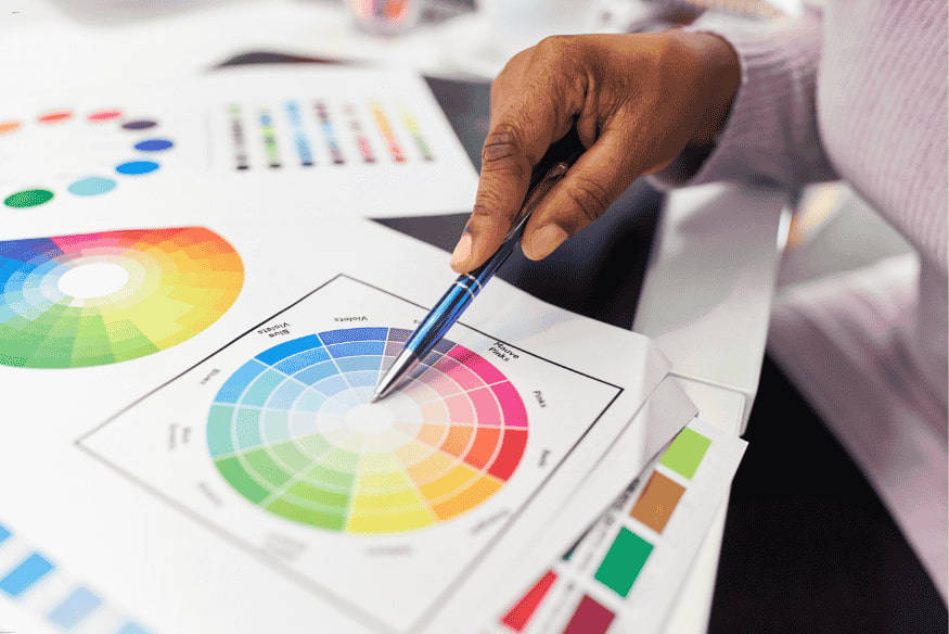 Designer escolhendo combinações no círculo cromático para criar paleta de cores harmoniosa.