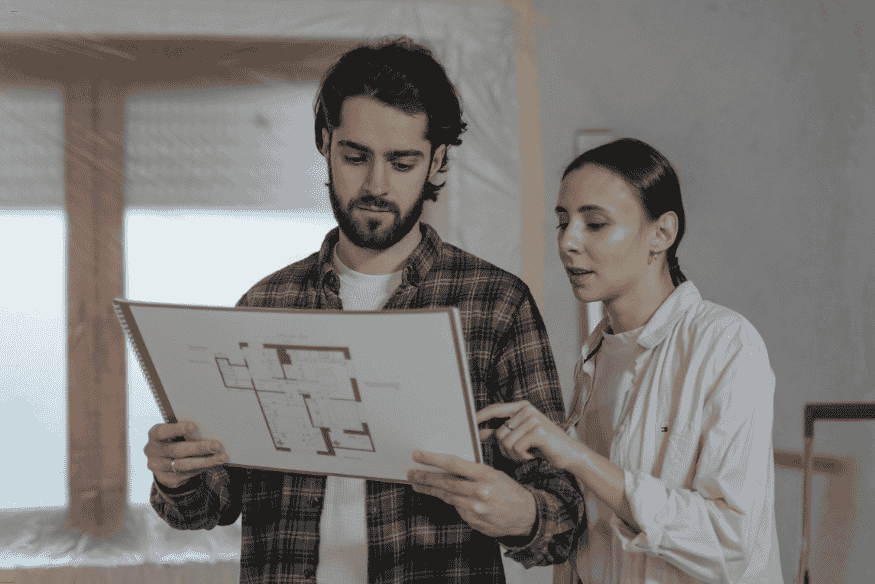 Casal analisando planta baixa para reforma residencial.