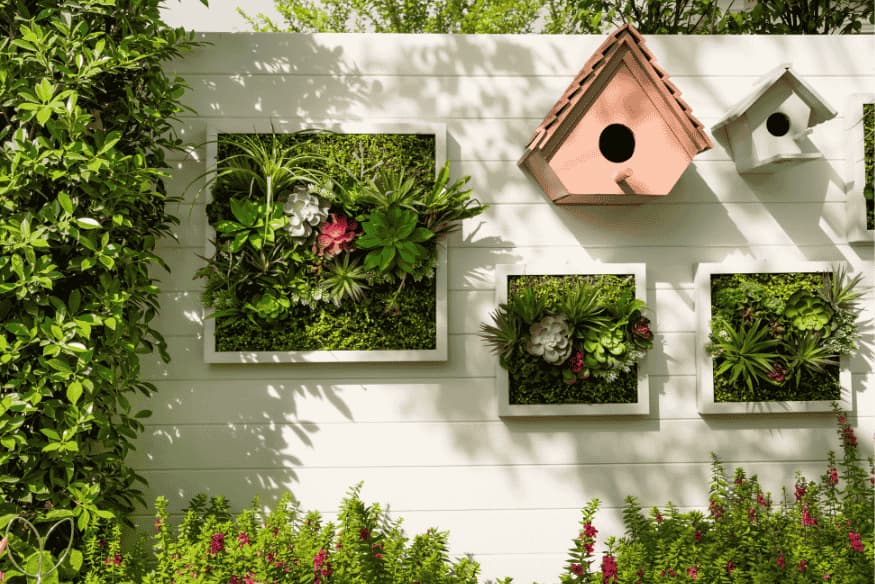 Jardim vertical decorando muro lateral com plantas e casinhas de pássaros.