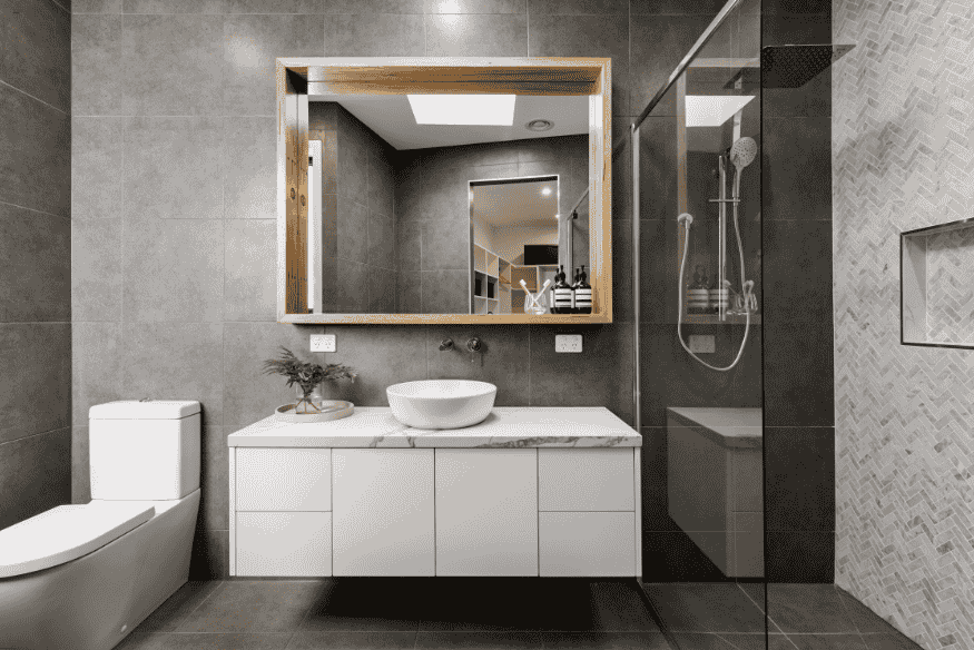 Banheiro pequeno com revestimento cinza e design sofisticado.
