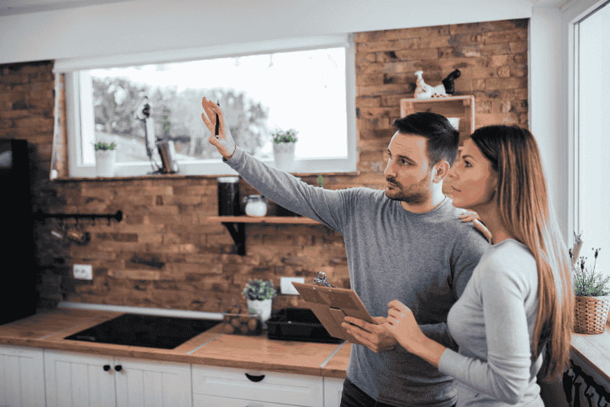 Casal analisando reforma de cozinha com prancheta em mãos