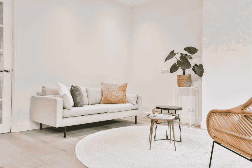 Sala de estar minimalista com sofá claro, tapete redondo e decoração em tons neutros.