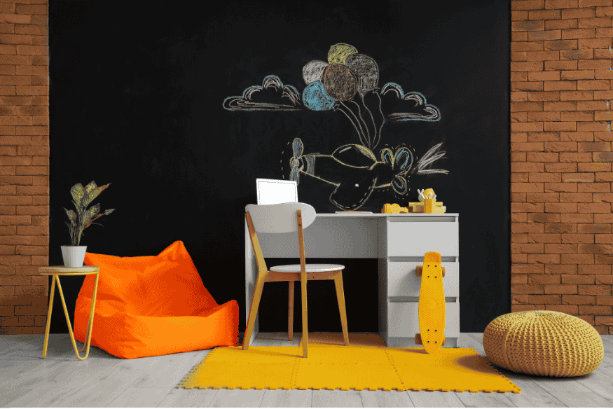 Escritório moderno com parede preta pintada com tinta lousa e desenhos coloridos.