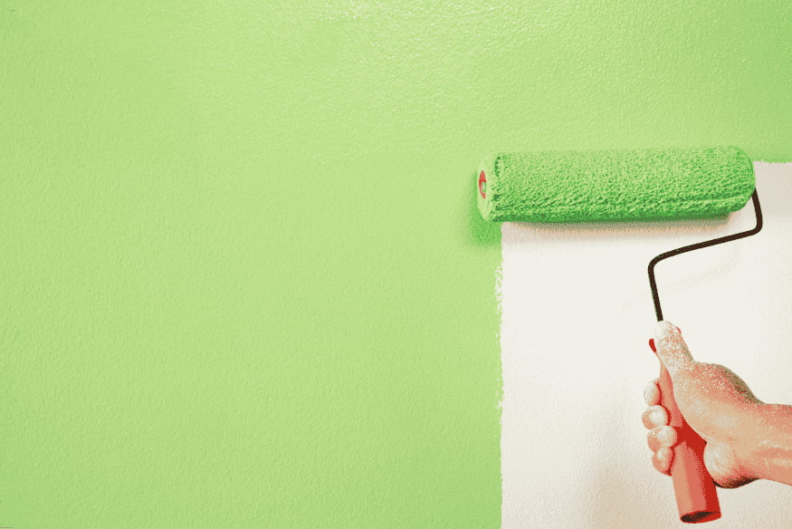 Pessoa pintando parede com rolo verde sobre fundo branco