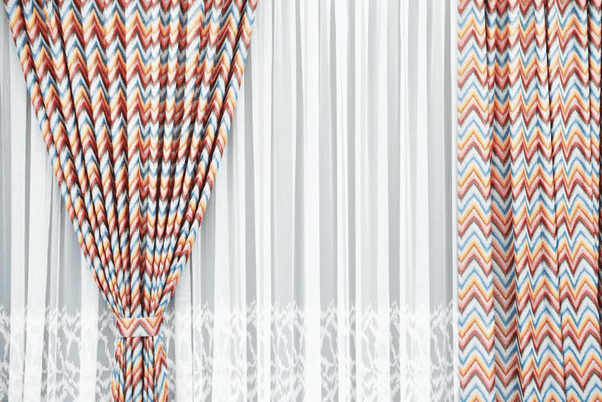 Cortinas com estampa colorida geométrica e tecido leve, trazendo estilo moderno.